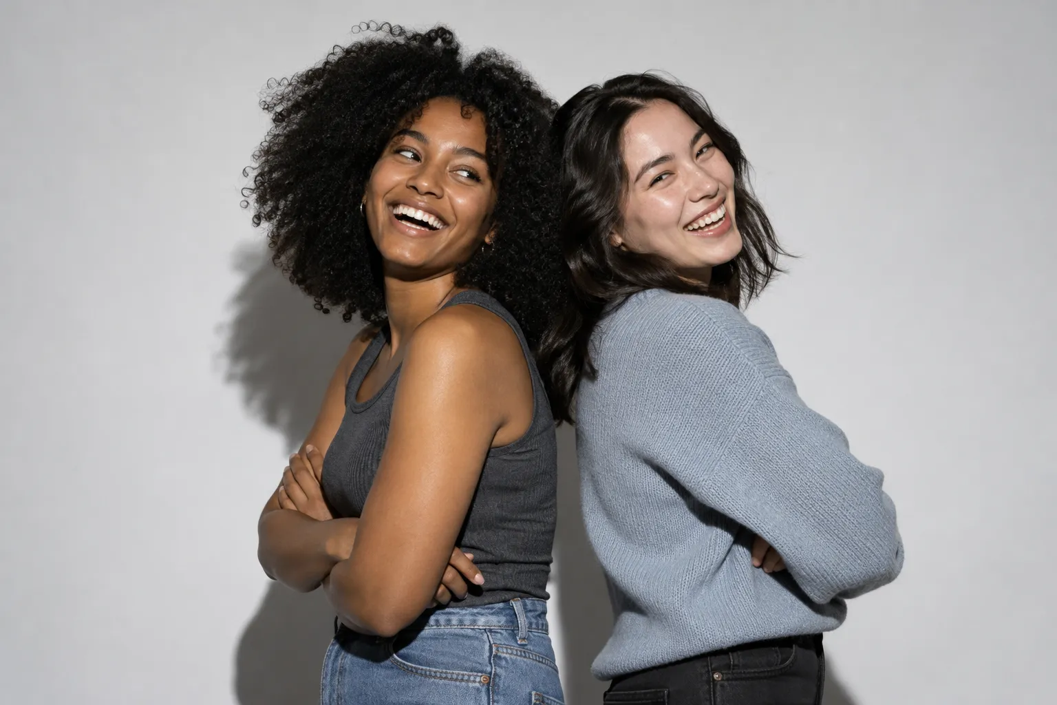 Two friends laughing back to back in the studio